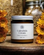 A jar of calendula cream with calendula flowers