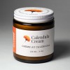 An amber glass jar of natural Calendula Cream