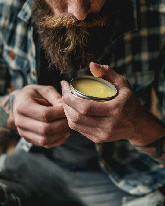 A bearded man applies Lovebee's natural beard balm