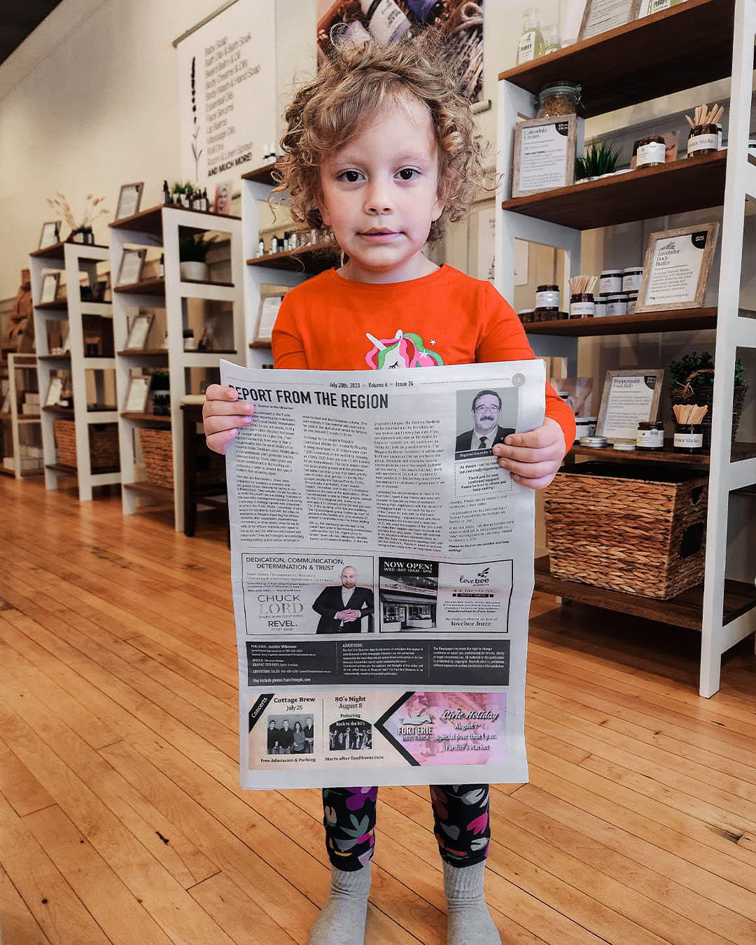 Little Eden At Lovebee Holding a Newspaper with an article about the store