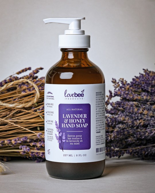 A natural lavender & honey liquid hand soap with a pump surrounded by dried lavender