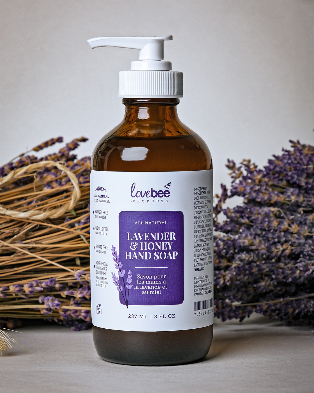 A natural lavender & honey liquid hand soap with a pump surrounded by dried lavender