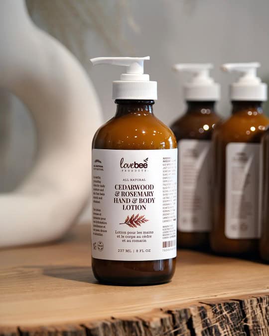 Amber glass bottle with a white pump on a wooden table filled with Cedarwood and Rosemary Lotion